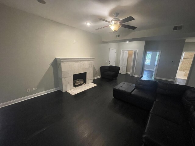 living area featuring visible vents, dark wood-style flooring, a fireplace, baseboards, and ceiling fan