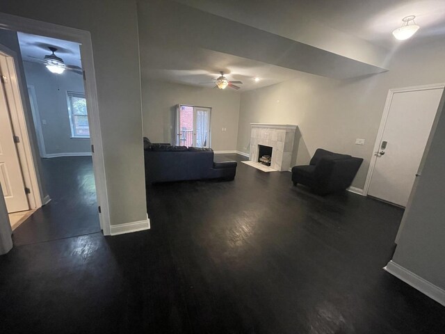 living room featuring baseboards, a ceiling fan, and a tile fireplace