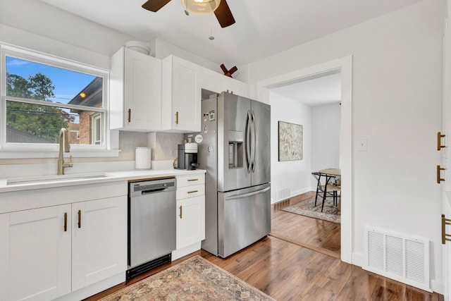 7428 N Odell Ave, Chicago, IL 60631 - kitchen with a sink, appliances with stainless steel finishes, visible vents, white cabinetry, and light wood-style floors