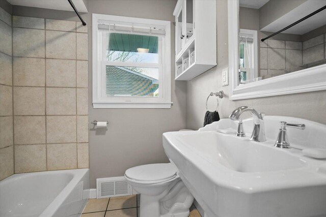 bathroom featuring toilet, tile patterned floors, baseboards, bathing tub / shower combination, and visible vents