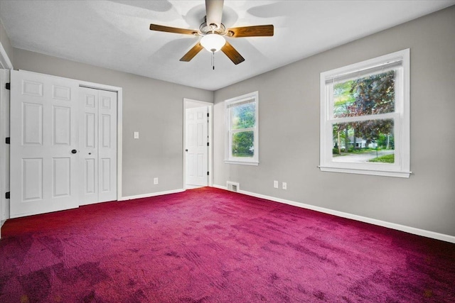 unfurnished bedroom with ceiling fan, visible vents, baseboards, a closet, and dark colored carpet