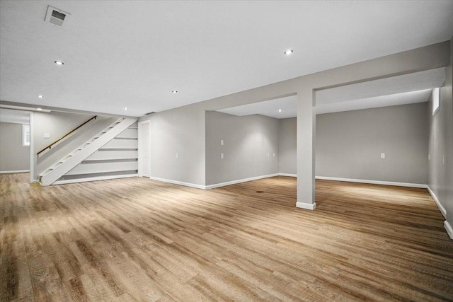 finished below grade area with baseboards, stairs, wood finished floors, and visible vents