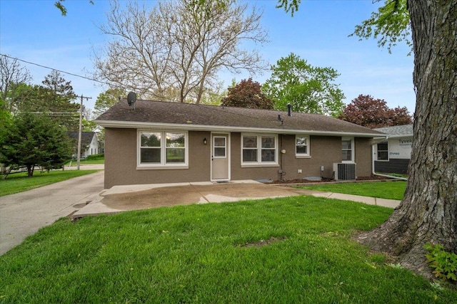 back of house with brick siding, central AC unit, roof with shingles, and a yard