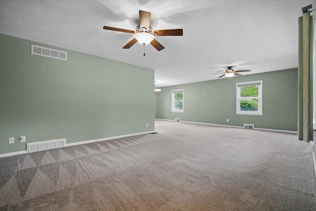carpeted empty room featuring visible vents and ceiling fan