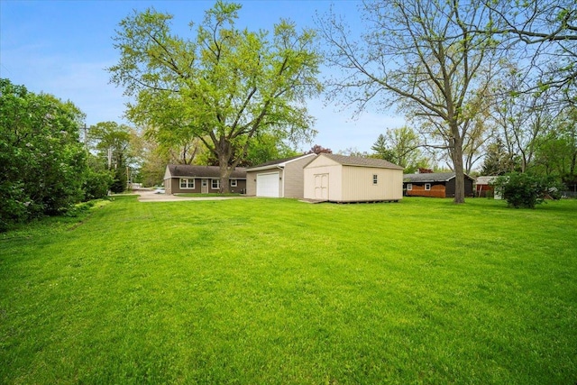 view of yard featuring a garage, an outbuilding, and driveway