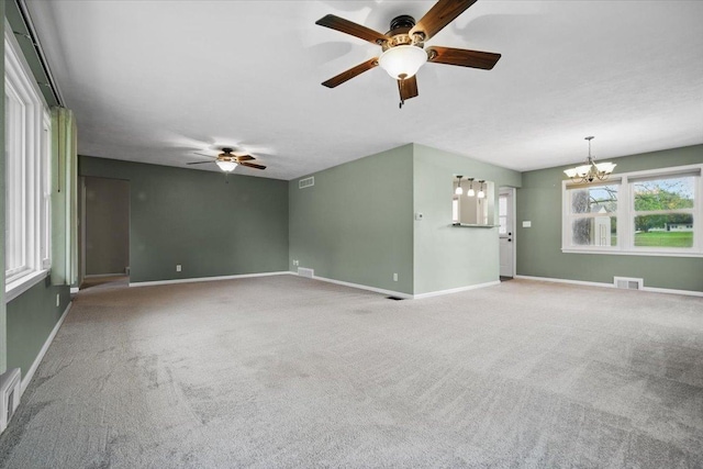 unfurnished living room with carpet floors, baseboards, visible vents, and ceiling fan with notable chandelier