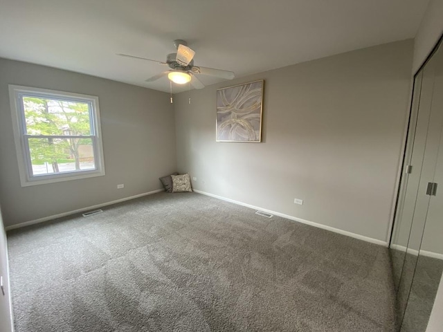 carpeted spare room featuring baseboards, ceiling fan, and visible vents