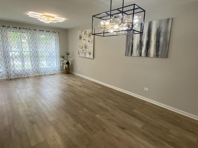 unfurnished dining area with an inviting chandelier, baseboards, and wood finished floors
