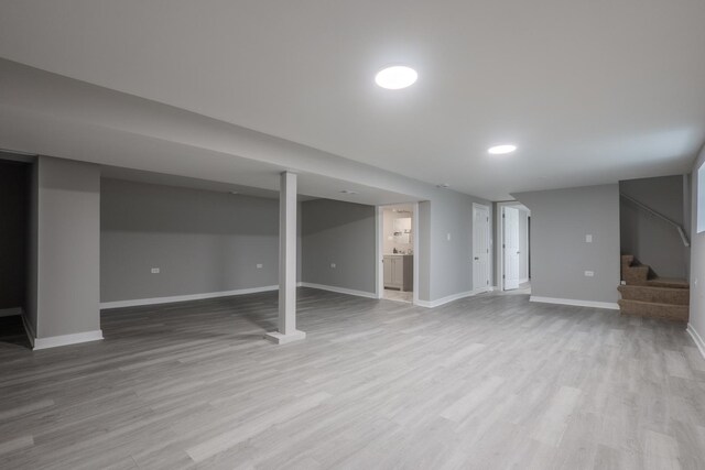 finished below grade area with baseboards, stairs, and wood finished floors