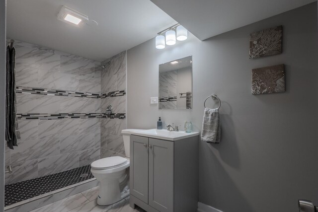 bathroom featuring vanity, marble finish floor, toilet, and tiled shower
