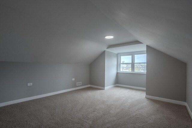bonus room with carpet floors, baseboards, vaulted ceiling, and visible vents