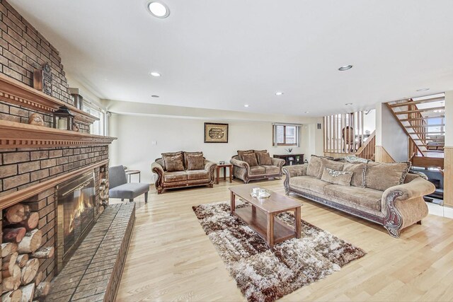 living area featuring recessed lighting, light wood-style flooring, stairway, and a fireplace