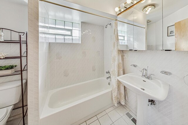 bathroom with visible vents, shower / bath combination with curtain, tile walls, tile patterned flooring, and toilet