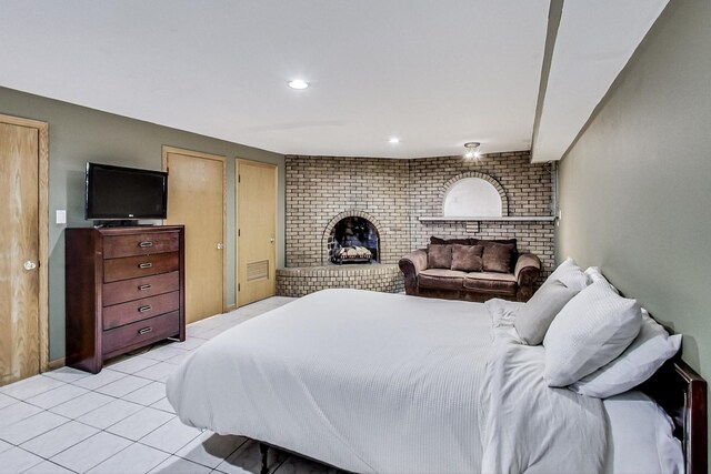 bedroom with recessed lighting, a brick fireplace, and light tile patterned floors