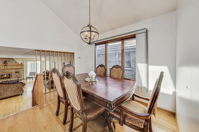 dining space with high vaulted ceiling, a notable chandelier, baseboards, and light wood-style floors