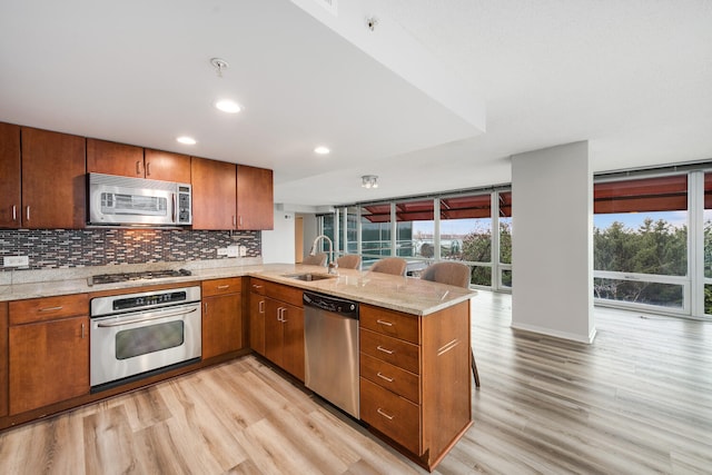 9715 Woods Dr Unit 700, Skokie, IL 60077 - kitchen with backsplash, a sink, a peninsula, stainless steel appliances, and light wood-style flooring