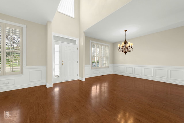 foyer entrance with wood finished floors, a wainscoted wall, and a notable chandelier