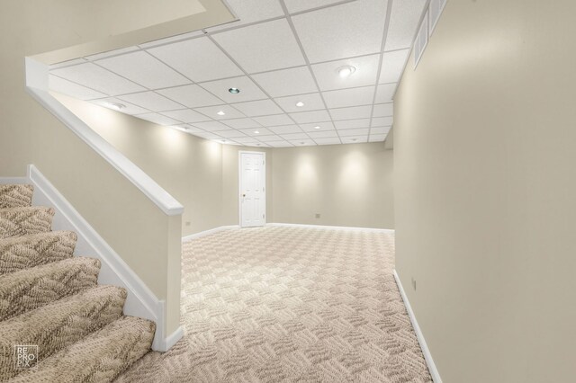 finished below grade area with carpet floors, stairs, recessed lighting, baseboards, and a drop ceiling