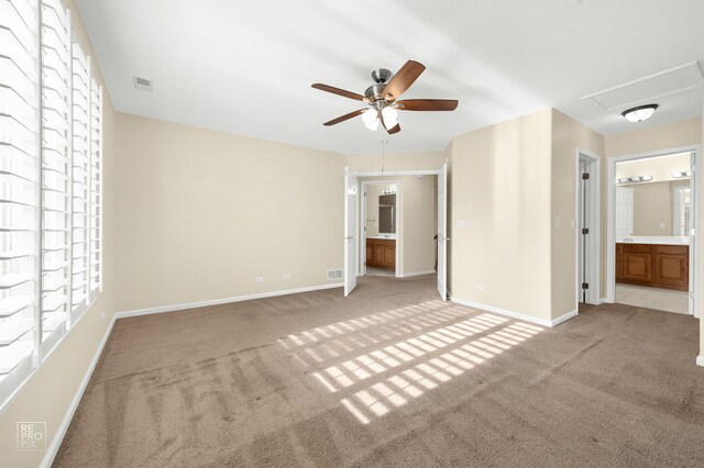 unfurnished bedroom featuring ensuite bathroom, baseboards, visible vents, and light carpet