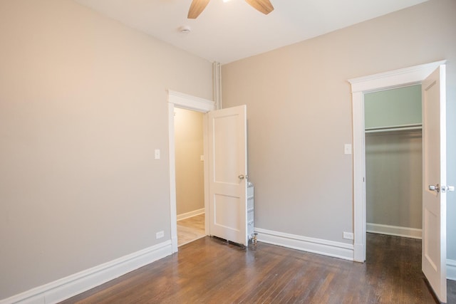 unfurnished bedroom featuring wood finished floors, baseboards, a closet, a spacious closet, and ceiling fan