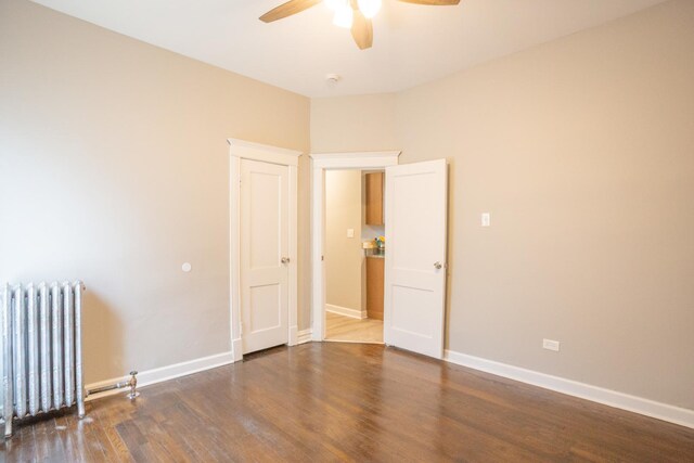 unfurnished room featuring radiator heating unit, ceiling fan, wood finished floors, and baseboards