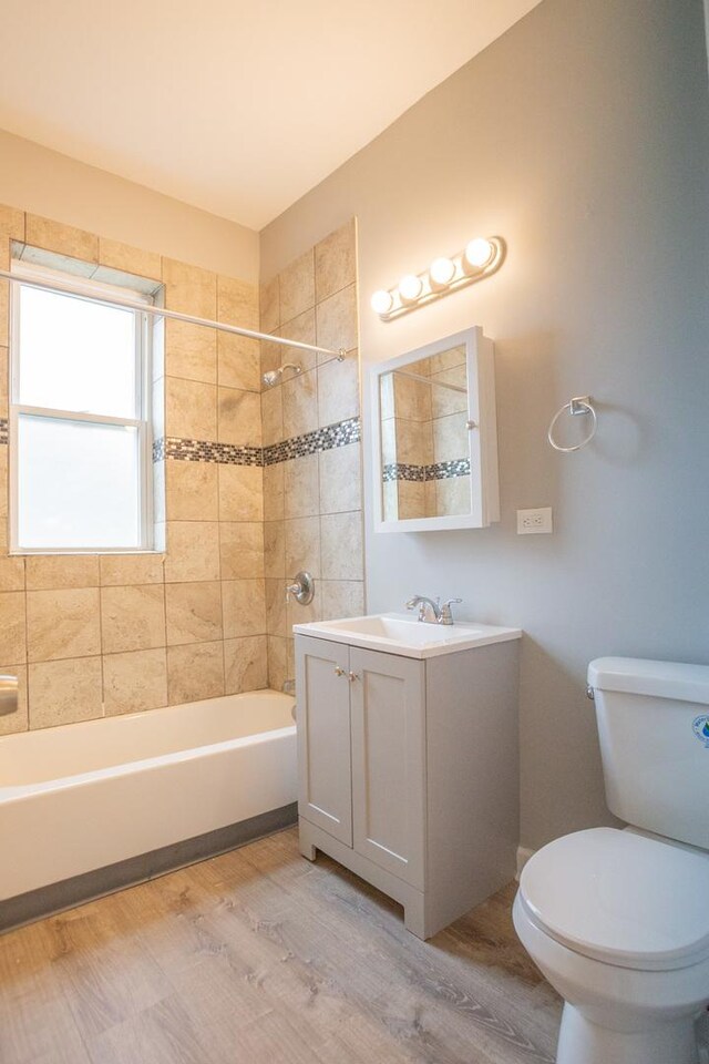full bathroom featuring bathing tub / shower combination, toilet, wood finished floors, and vanity