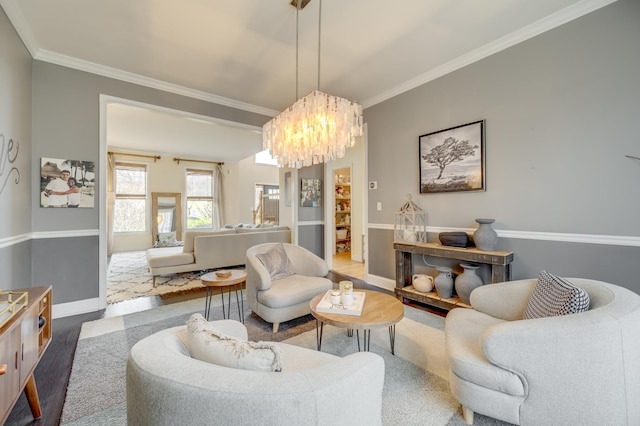 living area featuring an inviting chandelier, baseboards, crown molding, and wood finished floors