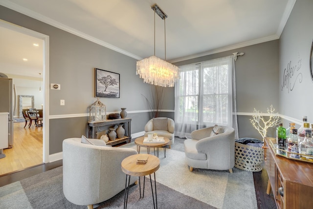 sitting room with an inviting chandelier, baseboards, ornamental molding, and wood finished floors