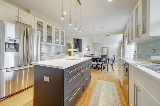 kitchen with white cabinets, stainless steel fridge with ice dispenser, light countertops, decorative backsplash, and a kitchen island