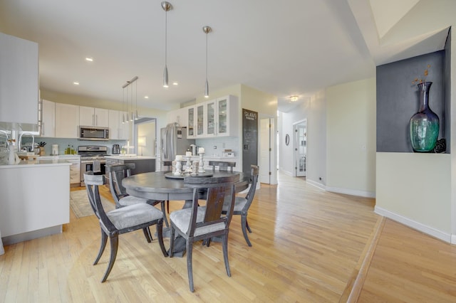 dining area with baseboards, recessed lighting, and light wood finished floors