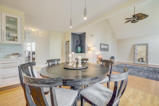 dining area with ceiling fan, baseboards, lofted ceiling, and light wood-type flooring