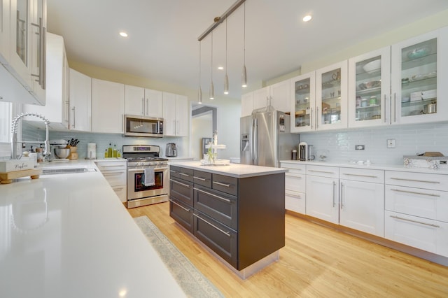 kitchen with white cabinets, a sink, light countertops, stainless steel appliances, and tasteful backsplash