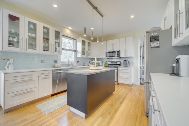 kitchen featuring light wood-style floors, tasteful backsplash, stainless steel appliances, and white cabinets