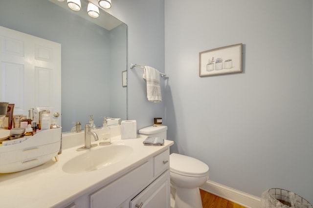 bathroom featuring vanity, baseboards, toilet, and wood finished floors