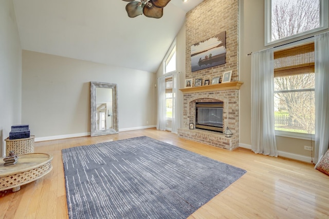 living room with a brick fireplace, high vaulted ceiling, ceiling fan, and wood finished floors