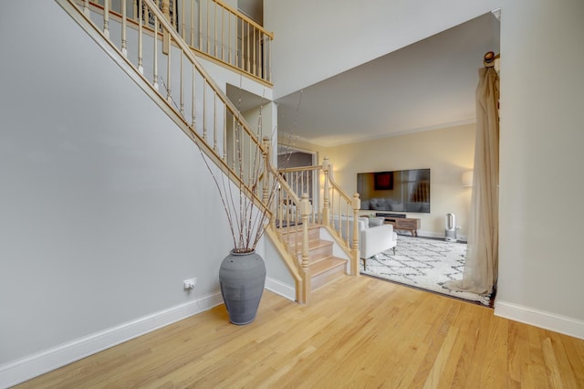 staircase with crown molding, baseboards, and wood finished floors