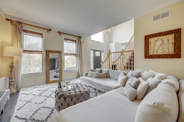 living area featuring visible vents, an inviting chandelier, wood finished floors, baseboards, and stairway