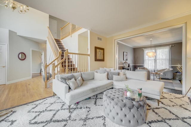 living room featuring visible vents, wood finished floors, stairway, an inviting chandelier, and ornamental molding
