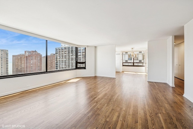 1410 N State Pkwy Unit 17B, Chicago, IL 60610 - spare room featuring wood finished floors, a chandelier, a view of city, and healthy amount of natural light