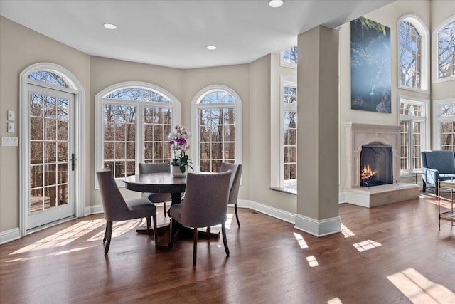 dining space with a fireplace, baseboards, a wealth of natural light, and wood finished floors