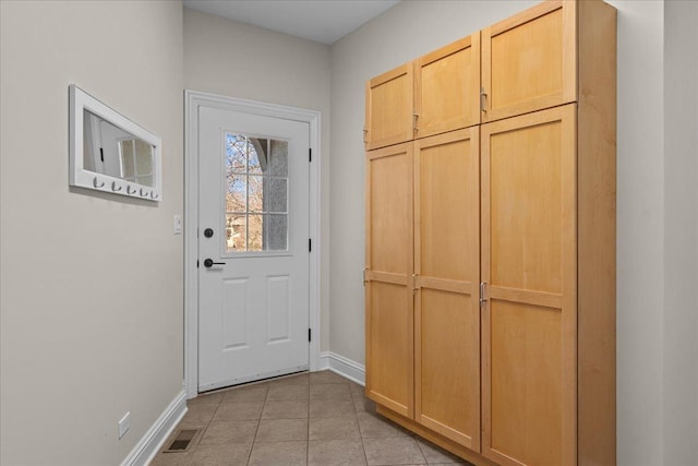 doorway featuring baseboards, light tile patterned flooring, and visible vents