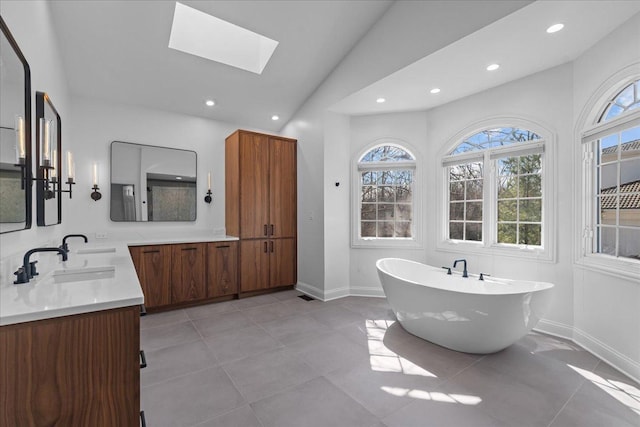 bathroom featuring a freestanding bath, recessed lighting, double vanity, and lofted ceiling with skylight