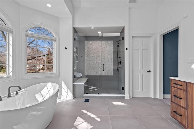 full bathroom with a freestanding bath, a shower stall, tile patterned floors, baseboards, and vanity