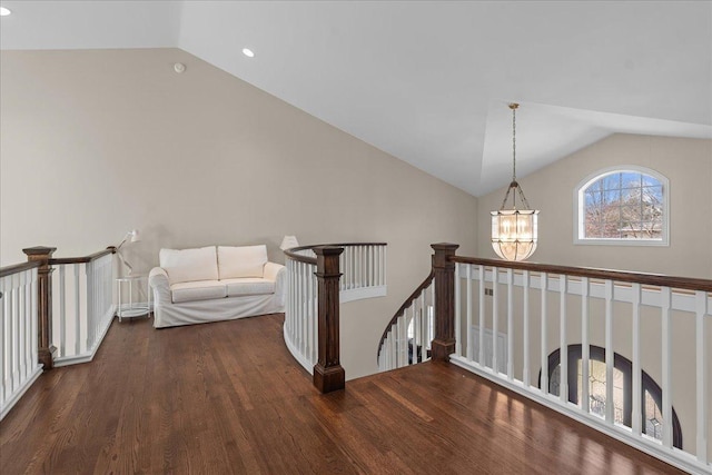 hallway featuring vaulted ceiling, an inviting chandelier, an upstairs landing, and wood finished floors
