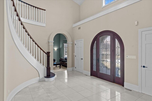 entrance foyer featuring arched walkways, a high ceiling, visible vents, and baseboards