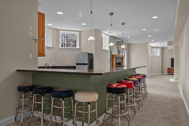 kitchen with brown cabinets, dark countertops, freestanding refrigerator, recessed lighting, and baseboards
