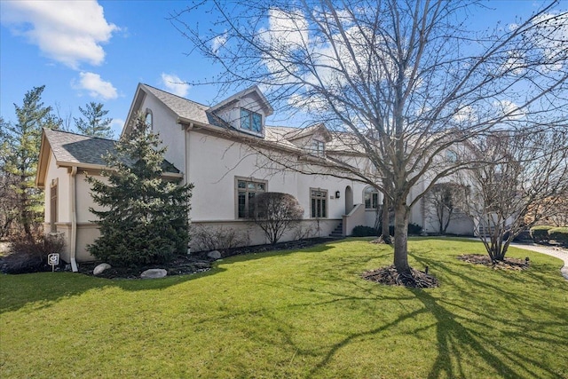 view of side of home with stucco siding and a yard