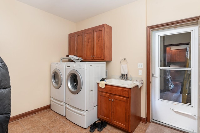 laundry room featuring washing machine and clothes dryer, baseboards, a sink, and cabinet space