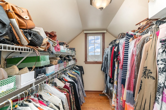 spacious closet with lofted ceiling and wood finished floors