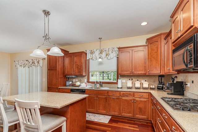 kitchen with light stone countertops, a breakfast bar, a sink, stainless steel appliances, and dark wood-type flooring